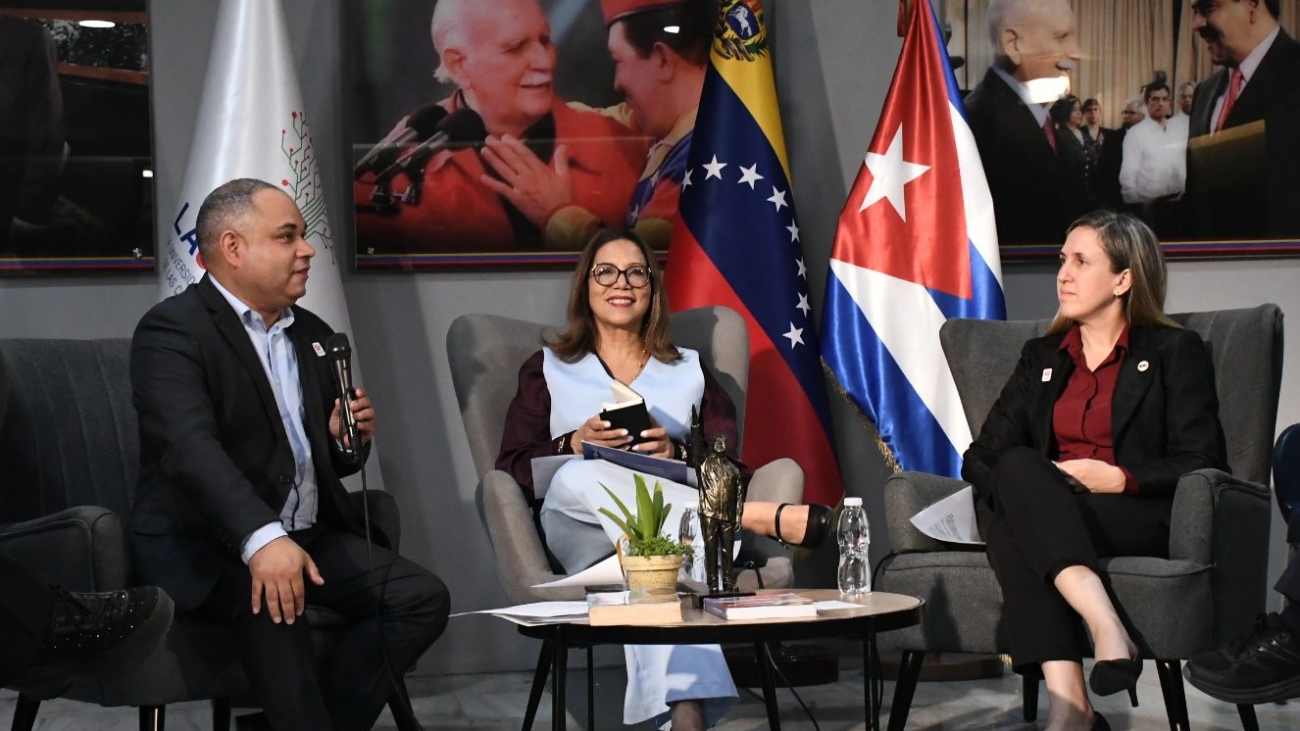 Las autoridades y ponentes durante la Sesión Especial de la Cátedra Internacional Hugo Chávez en LAUICOM, con las banderas de Venezuela y Cuba de fondo.