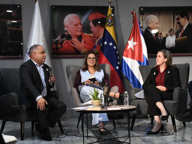 Las autoridades y ponentes durante la Sesión Especial de la Cátedra Internacional Hugo Chávez en LAUICOM, con las banderas de Venezuela y Cuba de fondo.